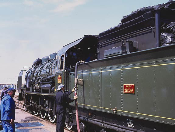 231G558 is normally watered with the aid of hoses and the special attachment seen here modified so as not to damage the tender paint work. On the left is a member of the crew with characteristic black face. French coal, and the briquettes, produe a lot of dust covering the crew. No wonder they all wear goggles ! June 1 2003
