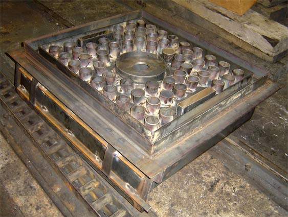 The panplate. This view shows the topside with the hole for mounting the burner prominent in the centre. The two slots are provided to allow the atomising steam superheater elements to be fitted. In due course the space between the air pipes etc was filled with fireclay. © Nigel Day The panplate. This view shows the topside with the hole for mounting the burner prominent in the centre. The two slots are provided to allow the atomising steam superheater elements to be fitted. In due course the space between the air pipes etc was filled with fireclay. © Nigel Day
