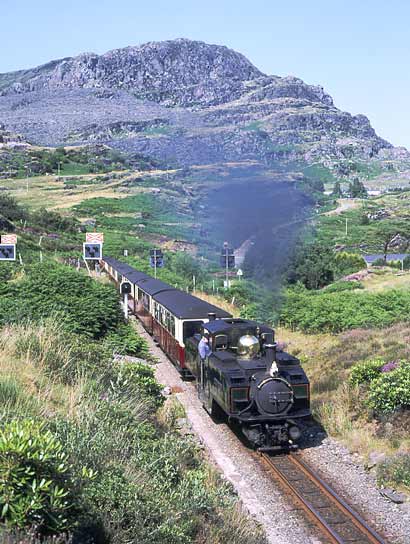 Double Fairlie 0-4-0+0-4-0 Earl of Meirioneth climbs on the 1 in 78 away from Tanygrisau with the 15:10 from Blaenau Ffestiniog to Porthmadog. It has just crossed Portal Road crossing. July 13 2003